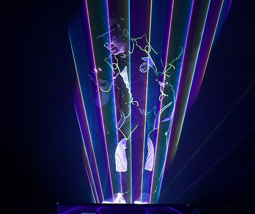 Lasershowact - Der Laserkünstler Jerry Pilar steht in einem farbigen Laserfächer auf der Bühne