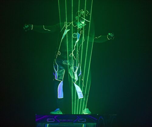 Lasershowact - Mann steht in einem farbigen Laserfächer auf der Bühne