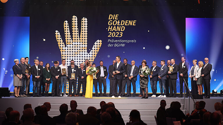 Die Preisträgerinnen und Preisträger der Goldenen Hand 2023 mit ihren Patinnen und Paten, sowie dem Moderationsduo Tina Babbel und Karl-Josef Thielen