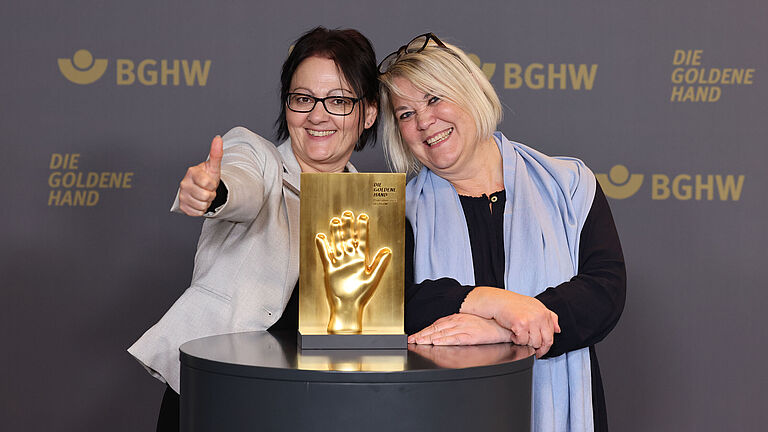 Zwei Frauen Posen mit dem goldene Hand Preis