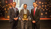 Drei Männer stehen vor der BGHW Stellwand und halten den Goldene-Hand-Preis