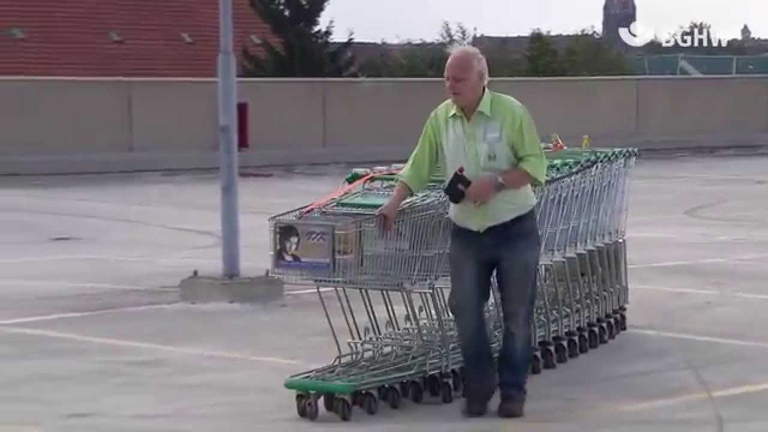 Einkaufswagen-Transporteur beim Transport von Einkaufswägen mit einer Einkaufswagen-Schiebehilfe