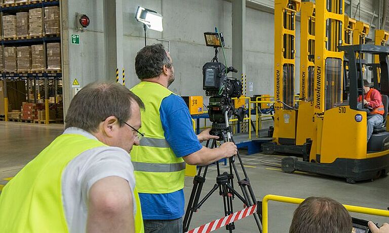 Kamerateam filmt einen Lagerarbeiter in einem Gabelstapler der Firma L'Oréal