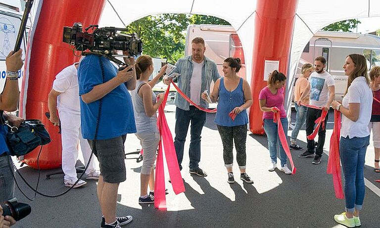 Angestellte von Rewe bei der Gesundheitswoche "Tour de Rewe" bei einem Fitnessspiel, begleitet von einem Kamerateam