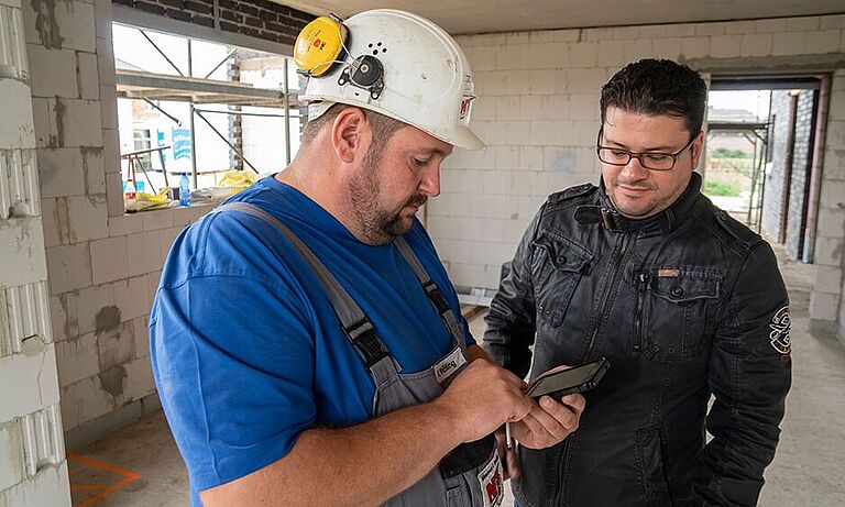 Zwei Bauarbeiter beim kontrollieren der baustellenbezogenen Checkliste