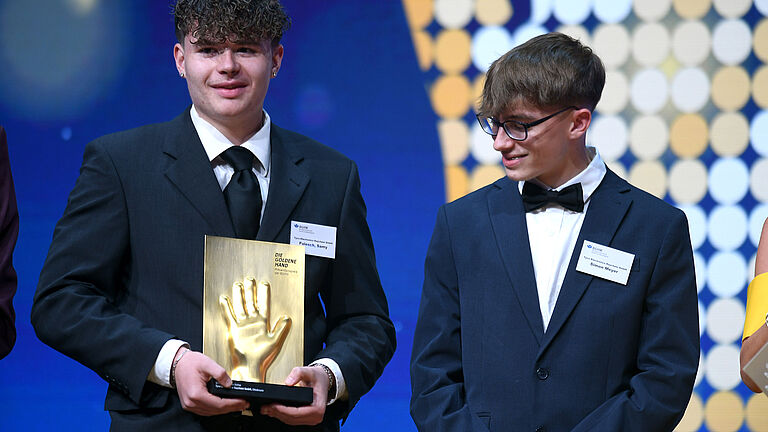 Zwei junge Männer halten den Goldene Hand Preis