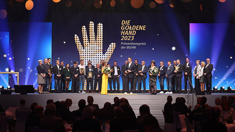 Die Preisträgerinnen und Preisträger der Goldenen Hand 2023 mit ihren Patinnen und Paten, sowie dem Moderationsduo Tina Babbel und Karl-Josef Thielen